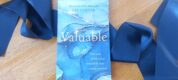 Valuable, by Liz Carter, on table, with blue ribbon background detail